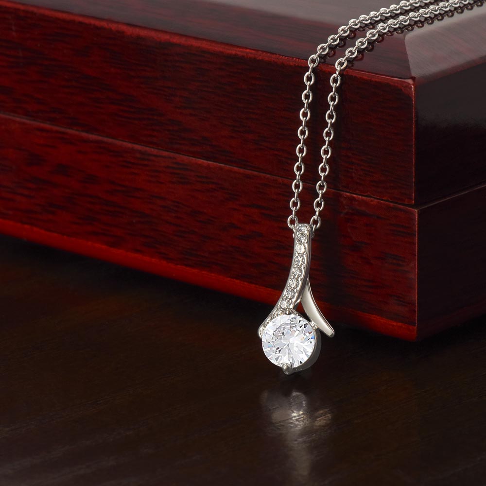Alluring Beauty Necklace with ribbon-shaped pendant on adjustable chain next to luxury gift box