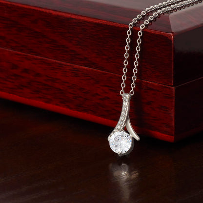 Alluring Beauty Necklace with ribbon-shaped pendant on adjustable chain next to luxury gift box