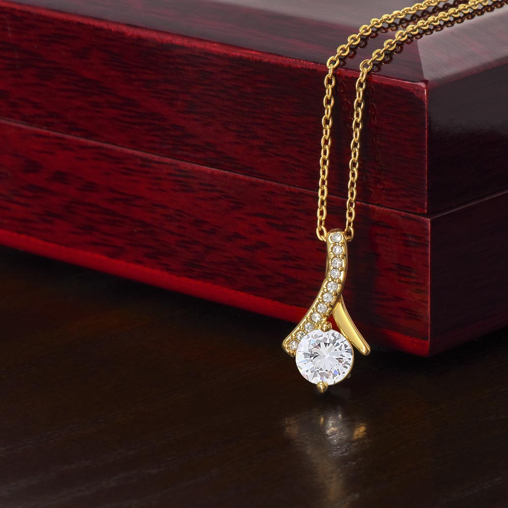 Alluring Beauty Necklace with ribbon-shaped pendant on adjustable chain next to luxury gift box